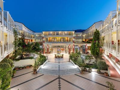 Helder verlichte hotelbinnenplaats met trappen en planten in de avond.