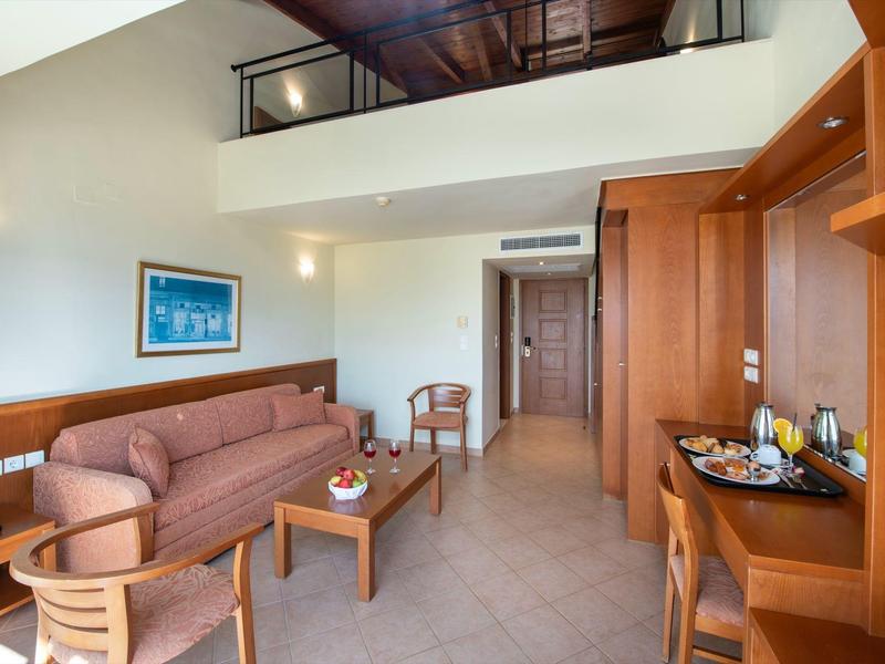 Helles Wohnzimmer mit braunem Sofa, Holzmöbeln, kleinem Tisch und Kunstbild an heller Wand.