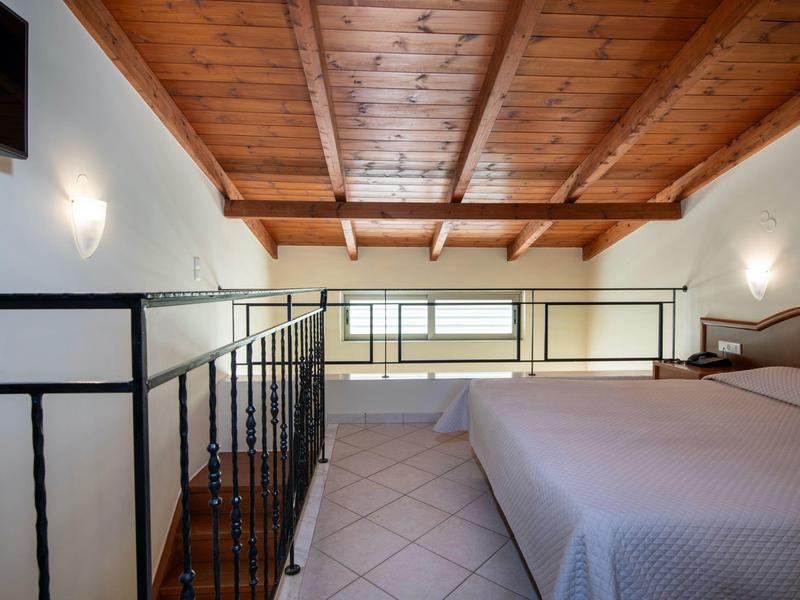 Gemütliches Schlafzimmer mit Holzbalkendecke, großem Bett und einem kleinen Fenster an der Wand.