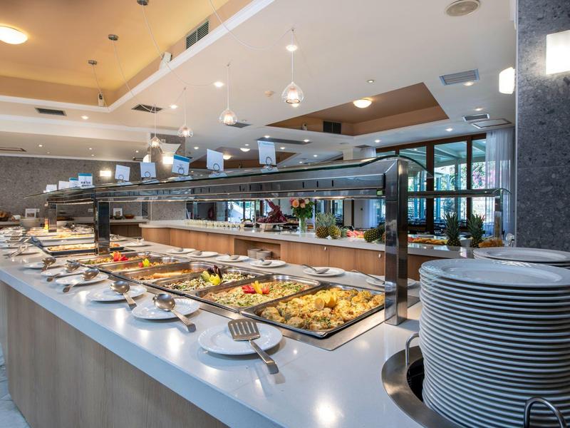 Buffet mit verschiedenen warmen und kalten Speisen in modernem, hell beleuchtetem Restaurant.