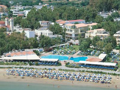 Kurort nadmorski z parasolami, basenami, zielenią i budynkami za brzegiem.