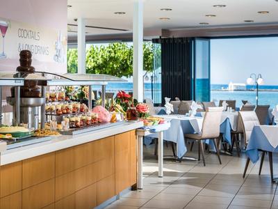 Bufet i jadalnia w nowoczesnej restauracji z widokiem na morze przez duże okna.