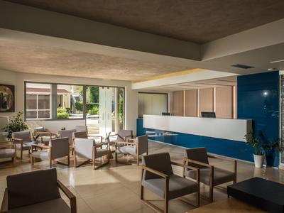 Nowoczesna lobby hotelowa z krzesłami, sofami i dużymi oknami z widokiem na ogród