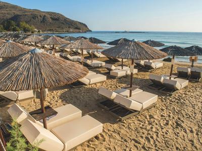 Plaża z leżakami i słomianymi parasolami nad morzem przy czystym niebie.