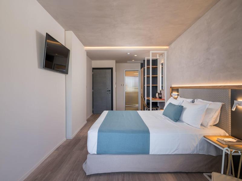 Nowoczesny pokój hotelowy z łóżkiem, telewizorem i stylowym oświetleniem.