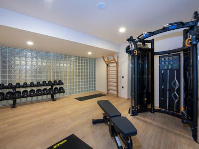 Gym room with workout bench, weights, and multi-gym equipment in a modern setting.
