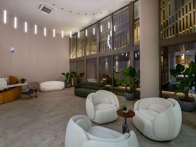 Modern hotel lobby area with comfortable armchairs, plants, and large glass windows.