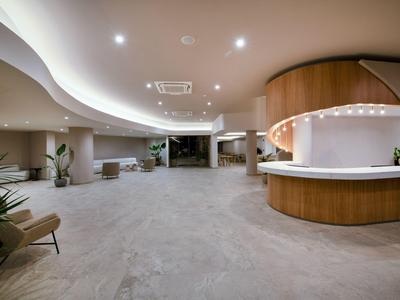 Spacious hotel lobby with modern design, round reception desk, and seating areas.