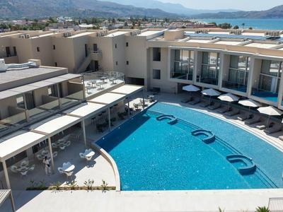 Modern hotel pool with comfortable loungers and sea view in a sunny coastal location.
