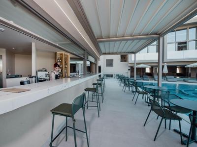 Área exterior moderna con bar, asientos y piscina en un hotel.