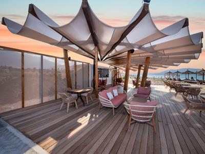 Terraza en la azotea al aire libre con asientos modernos y grandes toldos al atardecer.