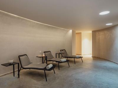 Área de lounge moderna en hotel con sillas minimalistas e iluminación indirecta.
