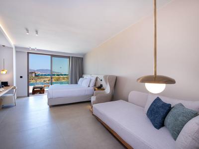 Habitación de hotel moderna con cama, sofá y balcón con vista al mar.