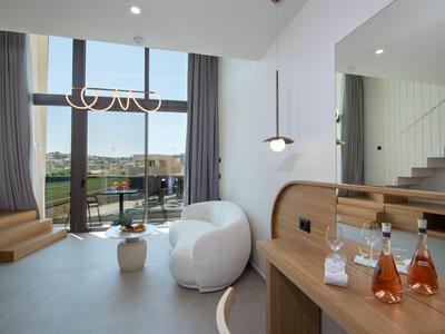 Habitación de hotel moderna con grandes ventanas y acceso a un balcón con vistas.