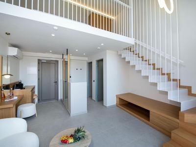 Habitación de hotel moderna con escalera, área de estar y espacio abierto en diseño minimalista.