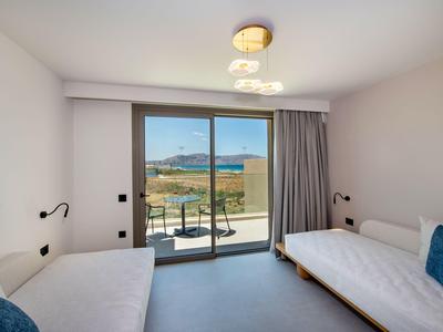 Habitación de hotel moderna con dos camas individuales y balcón con vista al mar.