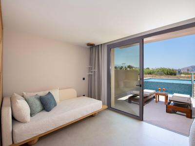 Habitación de hotel minimalista con sofá cama, grandes ventanas de cristal y vista a una vía fluvial.