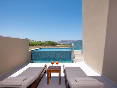 Dos tumbonas y una mesa junto a una pequeña piscina con vistas a las montañas bajo un cielo despejado.