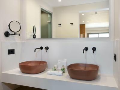 Doble lavabo con cuencos marrones y gran espejo en baño moderno.