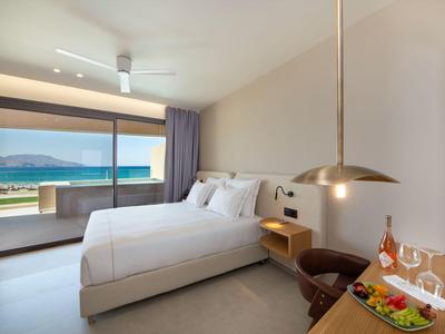 Habitación de hotel moderna con cama doble, terraza y vista al mar a la luz del día.