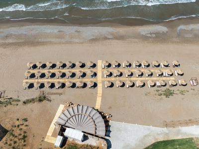 Vista aérea de una playa con filas de sombrillas y acceso a la playa.