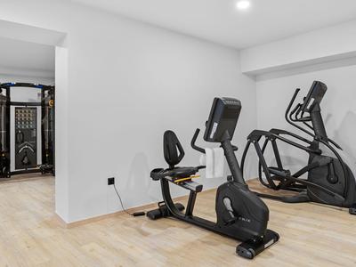 Bright fitness room with exercise equipment and wooden flooring in a hotel.