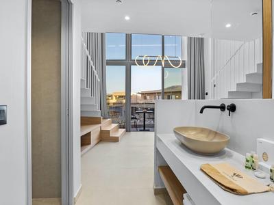 Moderner heller Raum mit Waschbecken, Holzablage und großen Fenstern mit Blick auf Terrasse.