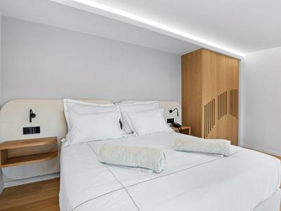 Modernes Hotelzimmer mit Doppelbett, weißen Bettwäsche und Holzmöbeln.
