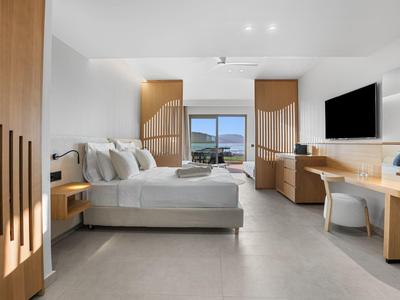 Moderner, hell eingerichteter Hotelzimmer mit großem Bett, Schreibtisch, TV und Meerblick vom Fenster.