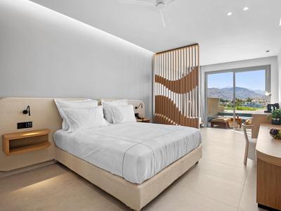 Modernes, helles Schlafzimmer mit großem Bett, Holztrennwand, Fensterblick und minimalistischer Einrichtung.