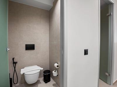 Kleines modernes Bad mit Wand-WC, Bidet-Dusche, schwarzem Mülleimer und weißem Toilettenpapierhalter.