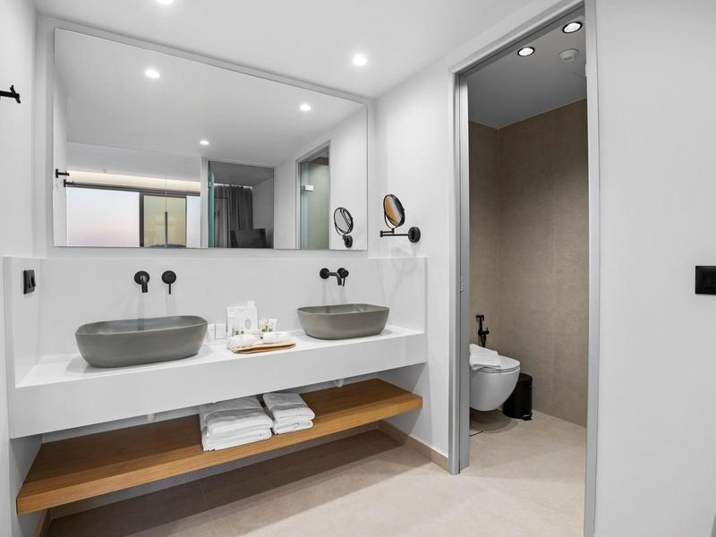 Modernes Badezimmer mit zwei grauen Waschbecken, großem Spiegel und separater Toilette.