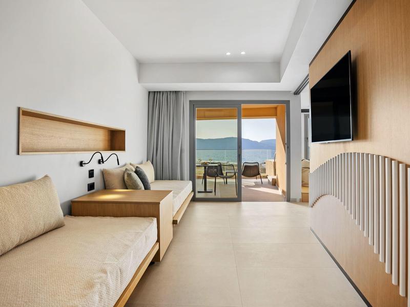 Moderner, heller Wohnraum mit beige Möbeln, großem Fenster und Blick auf Terrasse und Berge.