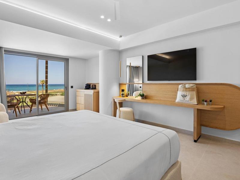 Modernes Hotelzimmer mit großem Bett, Balkon mit Meerblick und hellem Holzmöbeln.