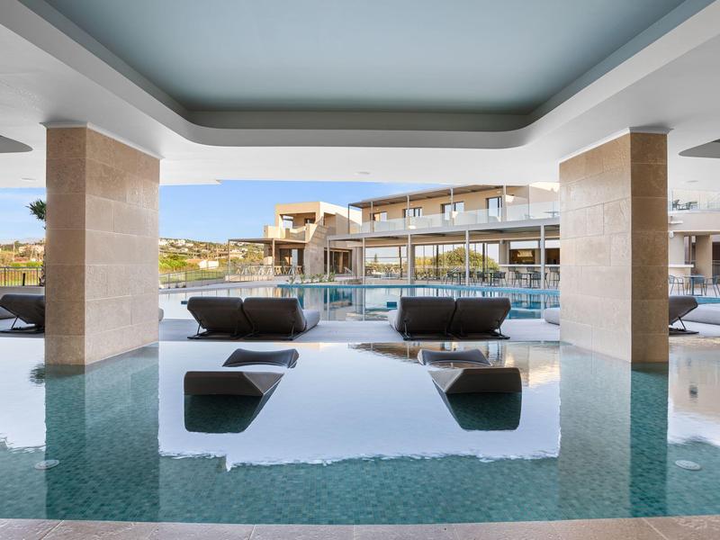 Moderner Poolbereich mit Lounge-Möbeln, Säulen und klarem Wasser unter überdachtem Bereich.