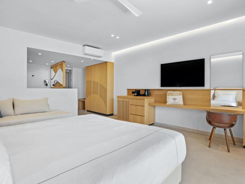 Modernes, helles Schlafzimmer mit großem Bett, Schreibtisch, Sofa und minimalistischem Dekor.