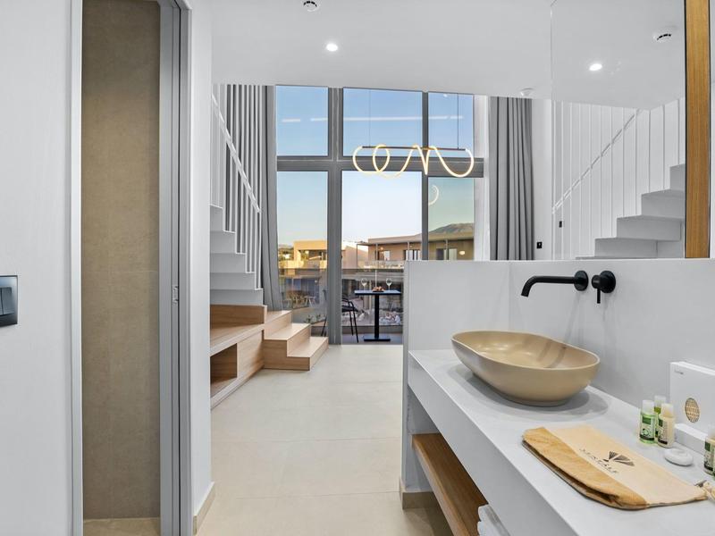 Moderner heller Raum mit Waschbecken, Holzablage und großen Fenstern mit Blick auf Terrasse.