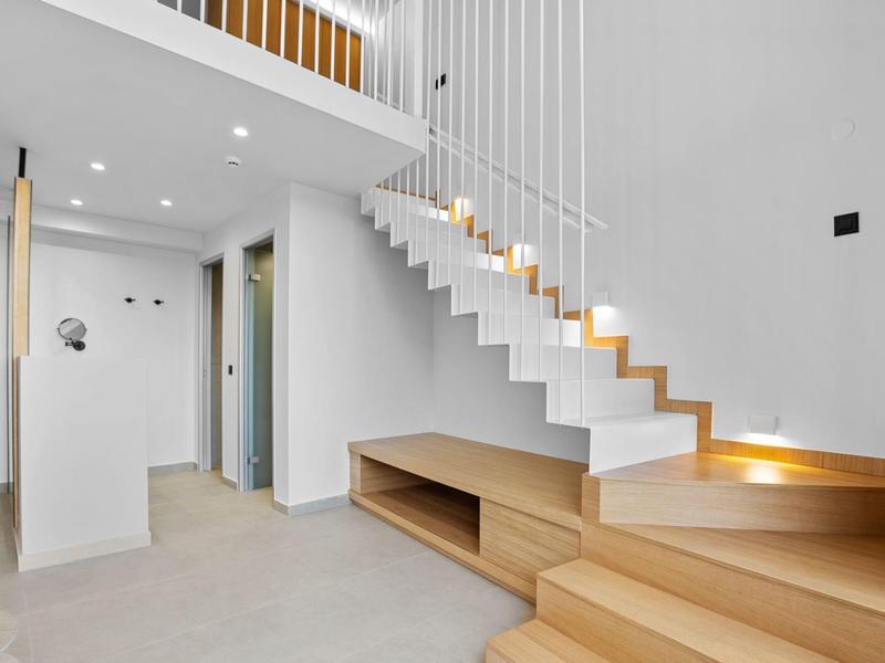 Moderner Innenraum mit offener Treppe aus Holz und Weiß, minimalistischem Design.