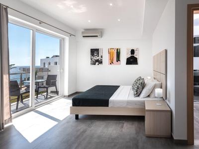 Habitación de hotel moderna con cama grande, balcón con vistas al mar y decoración minimalista.