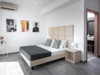 Camera d'hotel moderna con letto matrimoniale, tavolo e ingresso al bagno.