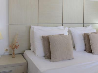 Hotelkamer met wit bed, lichte kussens en modern hoofdbord in neutrale tinten.