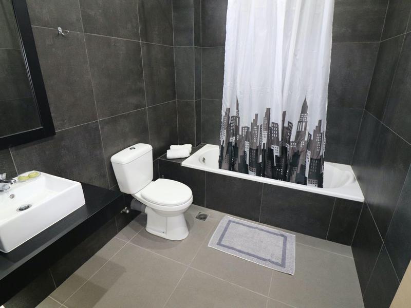 Baño moderno con inodoro, lavabo y bañera con cortina de ducha.