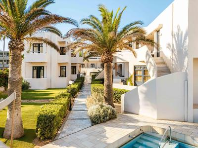 Hotel moderno con edificios blancos, palmeras y un camino de jardín bien cuidado