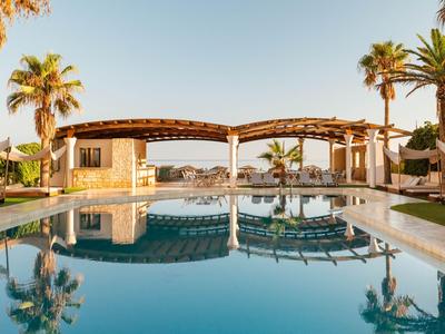 Una tranquila zona de piscina con palmeras y área de descanso bajo un cielo despejado.