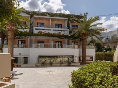 Edificio moderno de hotel con balcones, palmeras y jardín delantero bien cuidado en un día soleado
