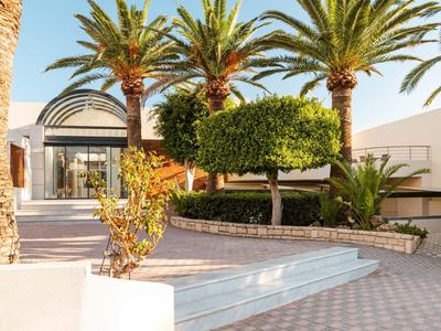 Hotel terrace with palm trees and manicured garden under clear sky