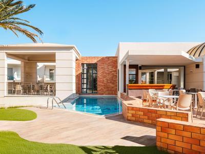 Área de piscina moderna del hotel con asientos y terraza soleada bajo un cielo despejado