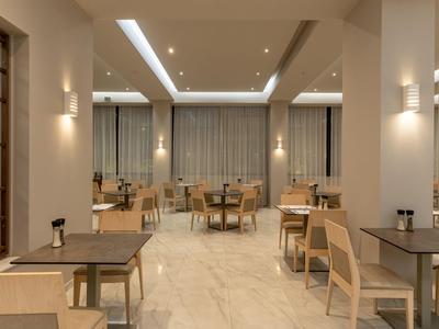 Área de comedor de hotel moderna con muebles de madera clara y tonos neutros.