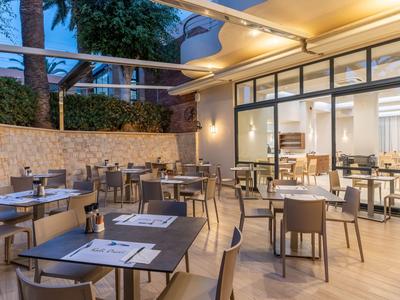 Área moderna de restaurante al aire libre con mesas y sillas en un entorno abierto.