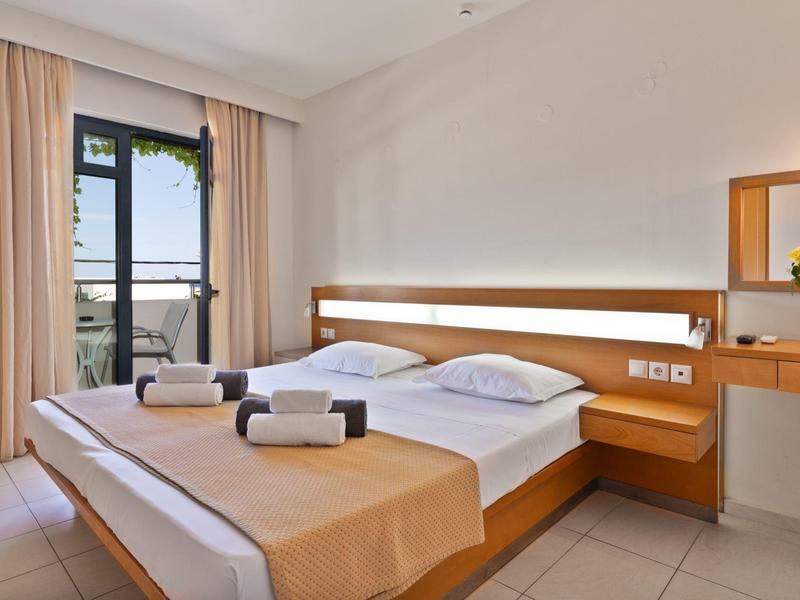 Bright hotel room with double bed, balcony, and sea view.